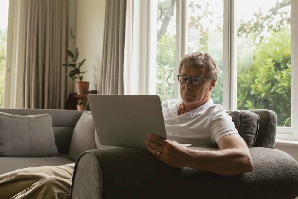 Senior,Man,Sitting,On,Gray,Sofa,In,Home,Living,Room